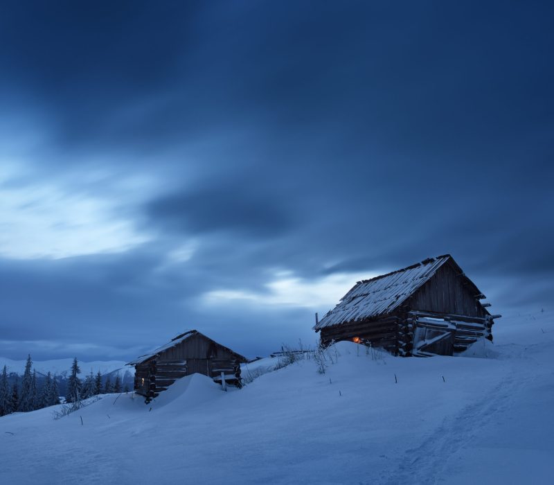 Night landscape. Winter in mountain village. Light in windows of wooden houses. Path in snow. Carpathians, Ukraine, Europe